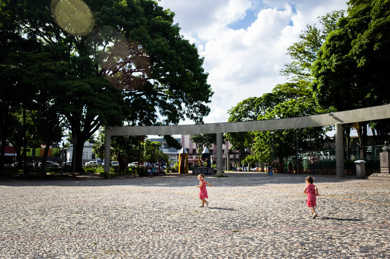 foto colorida. crianças correm pela praça.