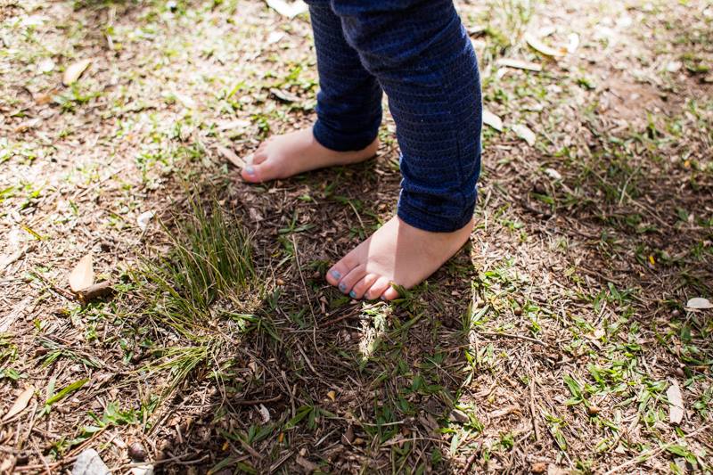 foto colorida. pés descalços de uma criança no gramado