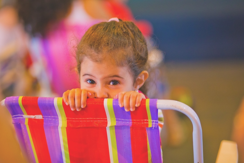 foto colorida. uma criança sentada em uma cadeira de praia olhando para o espectador.