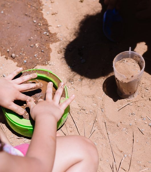 Ambiente natural, duas crianças brincam na areia