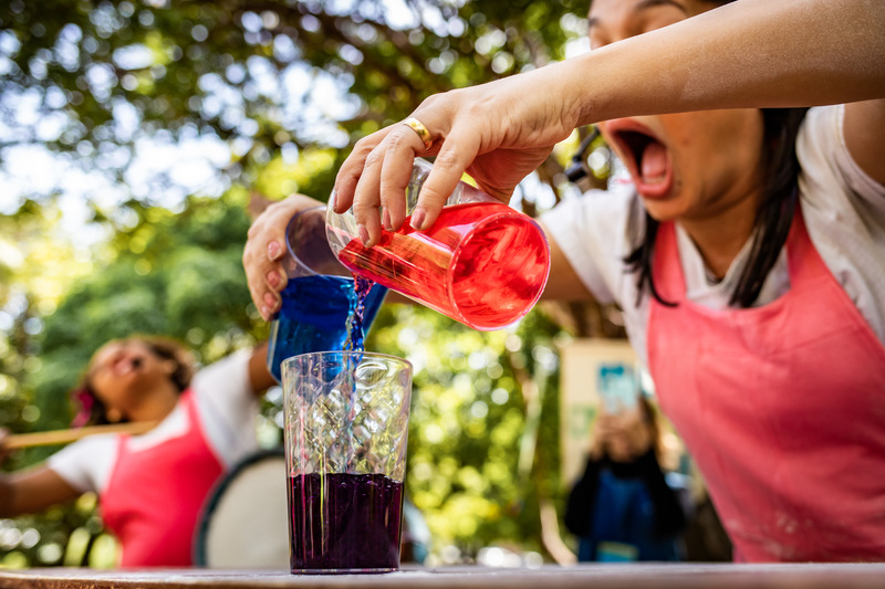 foto colorida. uma pessoa mistura bebidas em um copo durante a contação de histórias.